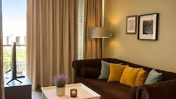 A modern living room with a brown sofa, a white coffee table, a lamp, and two framed pictures on the wall.