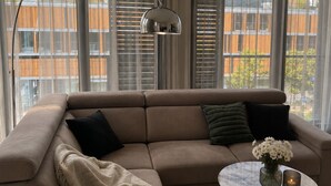 Een moderne woonkamer met een beige hoekbank, een ronde salontafel en een vloerlamp.