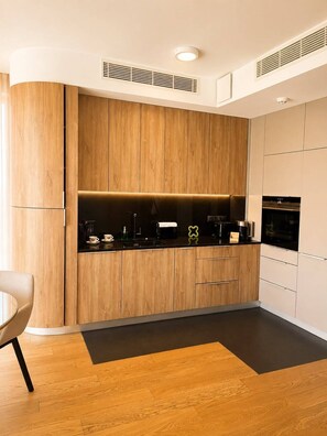 Una cocina moderna con armarios de madera, encimera negra y electrodomésticos integrados.