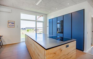 A modern kitchen with a central island, built-in appliances, and a large window. - Gorgeous home in Børkop with sauna (Børkop)