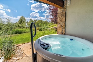 A hot tub with a view of a garden and a stone wall. - Storm Meadows Retreat | Pool & Hot Tub | Pet Friendly (Steamboat Springs)