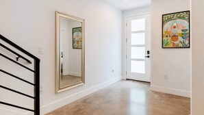 Un pasillo con un espejo grande, una puerta con paneles de vidrio esmerilado y una obra de arte enmarcada en la pared.