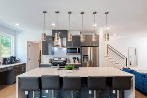 A modern kitchen with a central island, stainless steel appliances, and pendant lighting. - 6BR Hot Tub | 5 Min to DT | Large Groups Unit A (Austin)