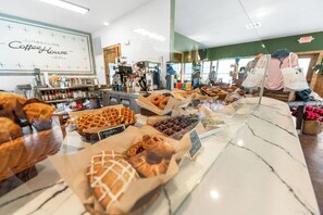 Ett skyltfönster med ett urval av bakverk och en skylt för ett kafé i bakgrunden.