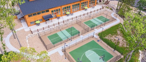 A multi-story building with a sports court, outdoor seating, and a parking lot.