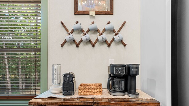 Et tekøkken med kaffemaskine, elkedel og kaffekrus hylder.