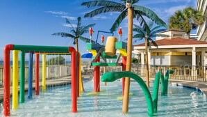 Ein Wasserspielbereich mit bunten Elementen und Palmen.