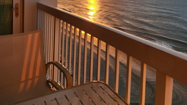 Ein Balkon mit Blick auf den Sonnenuntergang über dem Meer.