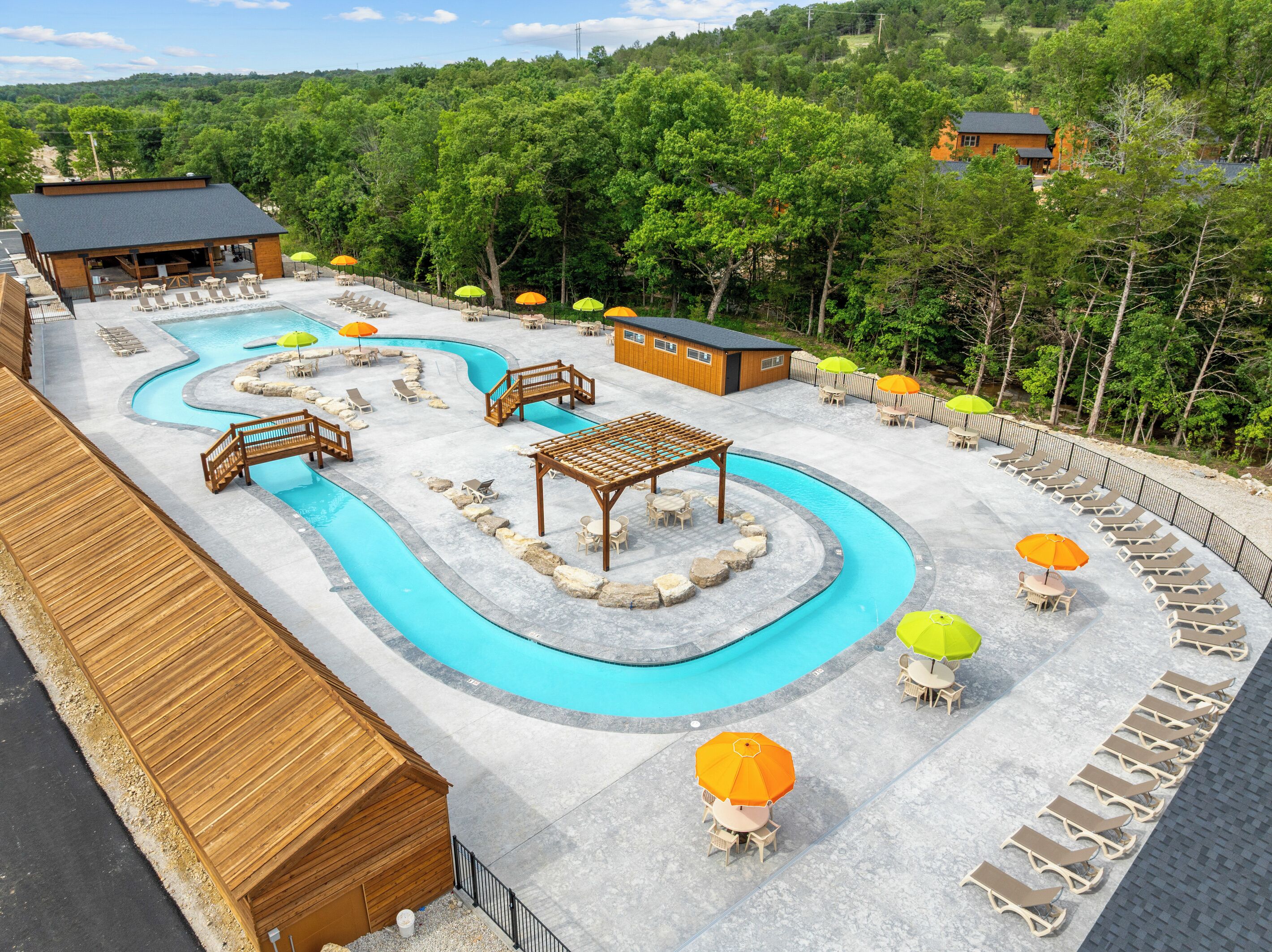 A pool area with lounge chairs, umbrellas, and a wooden structure.