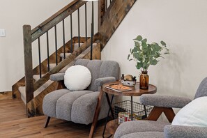Eine Treppe mit Holzbalkonen und ein grauer, gepolsterter Sessel mit weißem Kissen.