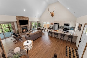 A spacious living area with a fireplace, a dining table, and a kitchen with a large island. - NEW! Hot Tub, Pools, Pickleball, Fishing, Trails (Hollister)