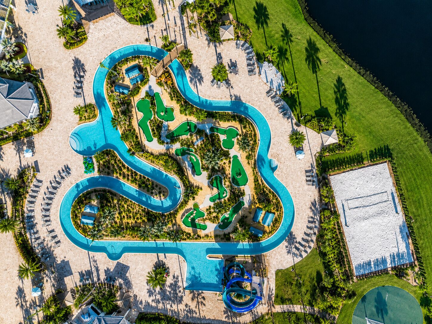 An aerial view of a resort with a large pool, multiple water slides, and sun loungers.