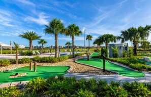 A miniature golf course with green putting greens, palm trees, and a clear blue sky. - Resort Style 4-bedroom townhome - Close to Disney (Kissimmee)