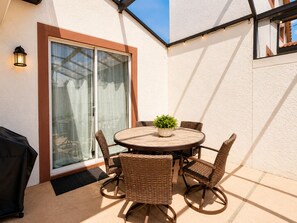 A patio with a round table, wicker chairs, a potted plant, and a grill. - Resort Style 4-bedroom townhome - Close to Disney (Kissimmee)
