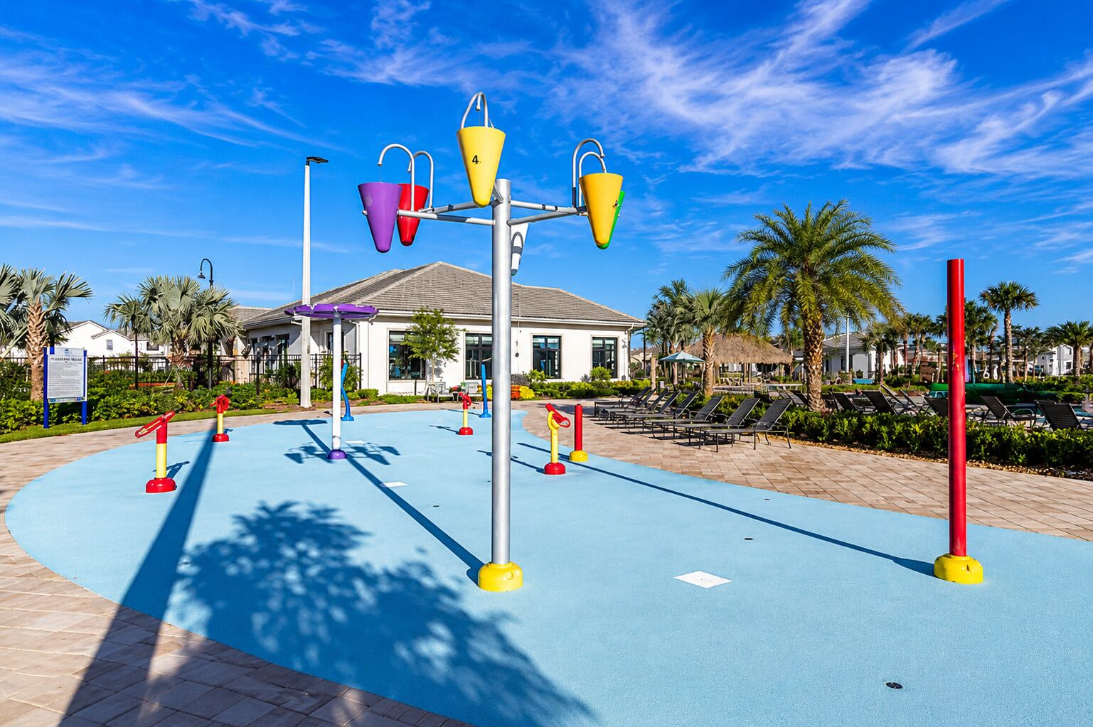 A playground with colorful equipment, a pool area, and a building with a white facade in the background.