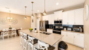 A modern kitchen with a central island, stainless steel appliances, and pendant lighting. - Resort Style 4-bedroom townhome - Close to Disney (Kissimmee)