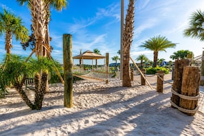 A sandy beach area with palm trees, a hammock, and a wooden structure. - Resort Style 4-bedroom townhome - Close to Disney (Kissimmee)