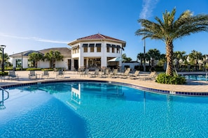 A swimming pool with lounge chairs and a building with a red roof. - Resort Style 4-bedroom townhome - Close to Disney (Kissimmee)