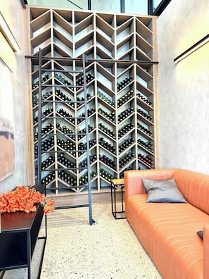 A wine cellar with a modern design, featuring a wall of wine racks and a seating area with a sofa and a small table. - Waterfall Executive Suite (Johannesburg)