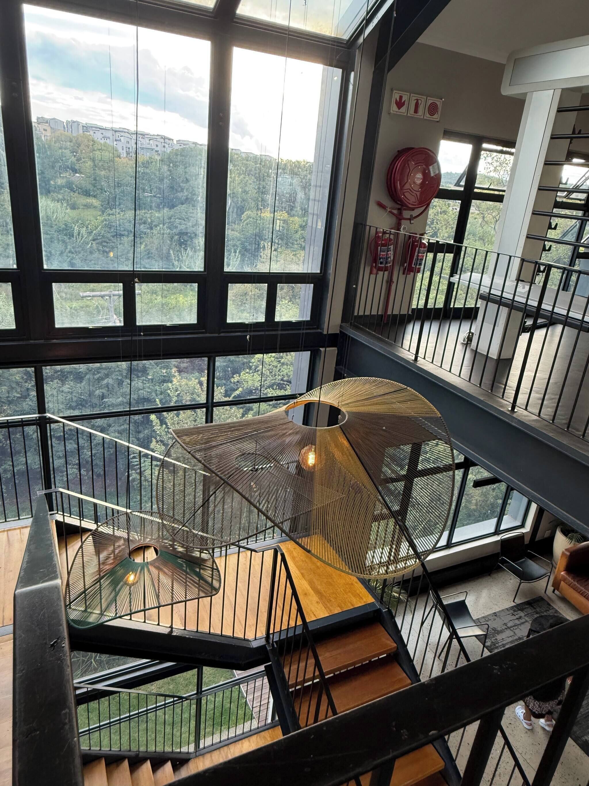 A multi-level interior with a spiral staircase, large windows offering a view of the outdoors, and a fire extinguisher mounted on the wall.