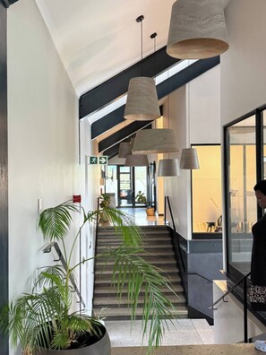 Ein modernes Interieur mit Treppe, hängenden Pendelleuchten und Topfpflanzen.