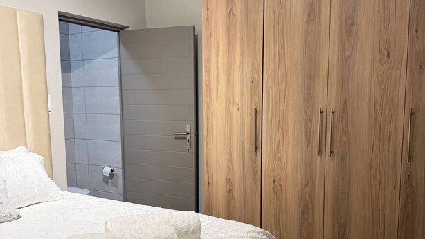 Ein Schlafzimmer mit einem Bett, einem Kleiderschrank und einer Badezimmertür.
