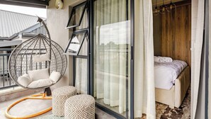Ein Schlafzimmer mit einem Bett, einem Hängekorbsessel und einem großen Fenster.