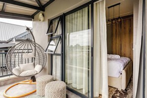 Ein Schlafzimmer mit einem Bett, einem Hängekorbsessel und einem großen Fenster.