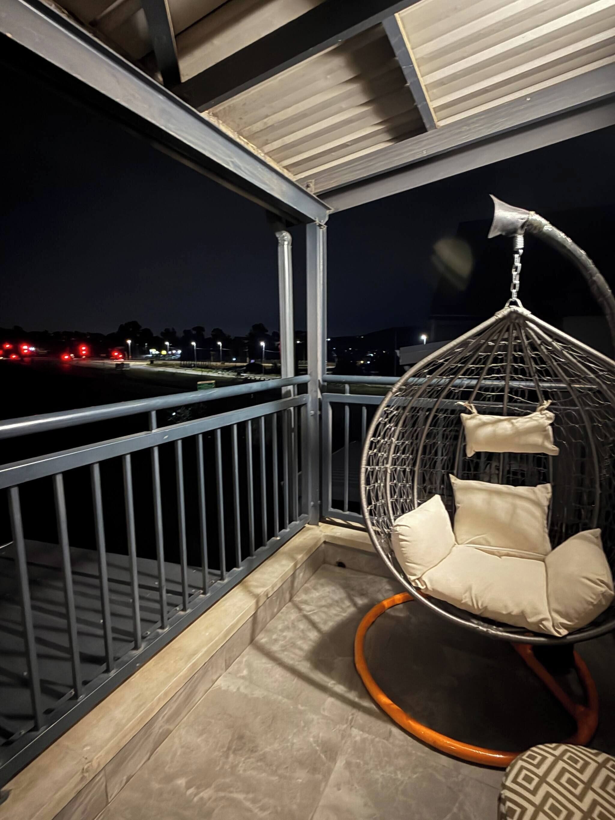 Un balcone con una sedia a dondolo e vista sulla strada di notte.