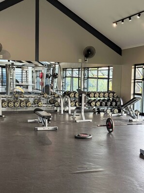 A gym with weightlifting equipment, benches, and dumbbells. - Waterfall Executive Suite (Johannesburg)