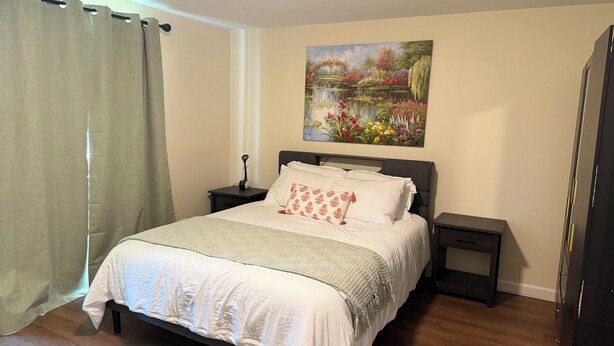 Una camera da letto con un letto, un comodino, un quadro e un armadio.