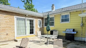 Un patio con mobili da esterno, un barbecue e un tavolo coperto.