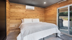 A room with a bed, wooden walls, a ceiling with recessed lighting, and a sliding glass door leading outside. - Everything, In Montana, All At Once (Saint Regis)