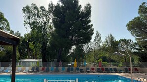 Una piscina con un cartello di divieto di accesso, circondata da sdraio e una recinzione.