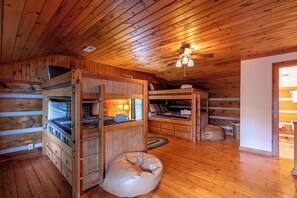 A cabin with wooden walls and floors, bunk beds, a ceiling fan, and a bean bag chair. - Caris Rivers Edge Cabin - game room, Twin Rivers mountain home in Boone, fire pit (Boone)
