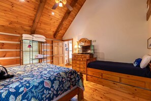 Ein Schlafzimmer einer Holzhütte mit Bett, Kommode und Spiegel.