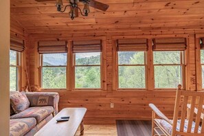 A wooden cabin interior with a sofa, a table, and a chair. - Lions Den- hot tub, pet friendly, 15 mins to Boone! (Vilas)