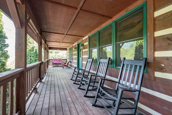 A wooden porch with rocking chairs and a bench, overlooking a forested area. - Lions Den- hot tub, pet friendly, 15 mins to Boone! (Vilas)