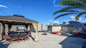 A covered patio area with outdoor furniture, a pool, and a gazebo.