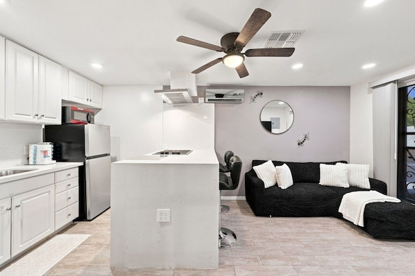 A modern kitchen with white cabinetry, a built-in island, and a ceiling fan.