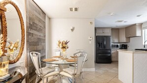 A modern kitchen with a built-in refrigerator, a dining area with a glass table and chairs, and a decorative mirror. - 7-Bedroom Ultra-Private Villa Estate •Pool & Gym (Phoenix)