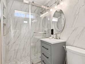 Ein modernes Badezimmer mit einer Duschkabine, einem Waschtisch mit Spiegel und einer Toilette.