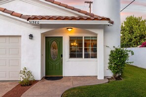 A house with a green door, a garage, and a small garden. - The Cove Villa | 3BR | Private Pool | Sleeps 6 (La Quinta)