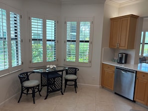 A kitchen with a dining table, chairs, cabinets, and a dishwasher. - Renovated Ravenna first floor townhome in exclusive Pelican Marsh. (Naples)