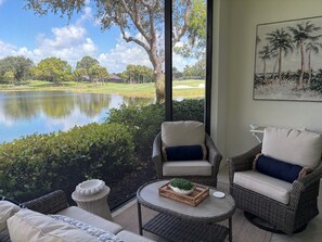A room with wicker furniture, a view of a golf course, and a pond. - Renovated Ravenna first floor townhome in exclusive Pelican Marsh. (Naples)