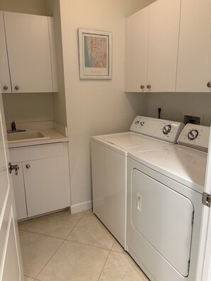 A laundry room with a washing machine, a dryer, and a sink. - Renovated Ravenna first floor townhome in exclusive Pelican Marsh. (Naples)