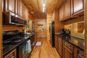 Cocina con armarios de madera, estufa de acero inoxidable y refrigerador.