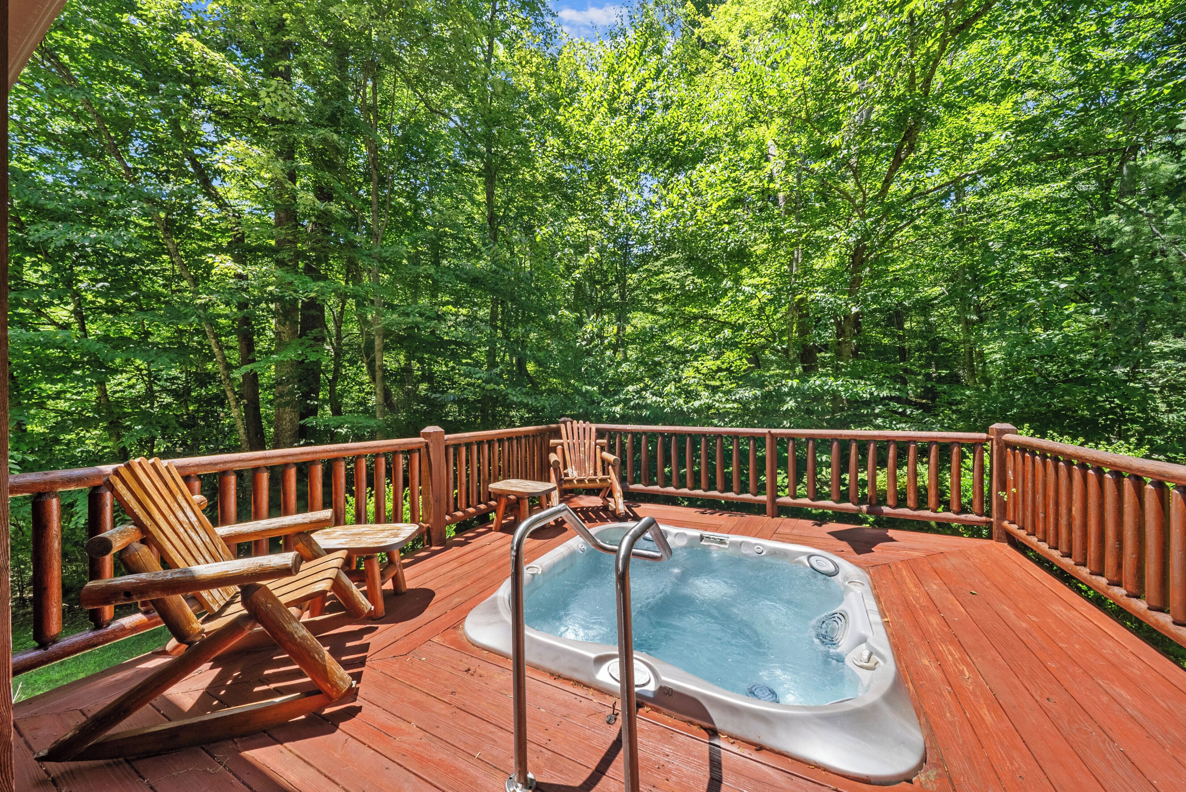 Une terrasse en bois avec un jacuzzi, des chaises et des tables en bois, le tout entouré d’arbres verdoyants.