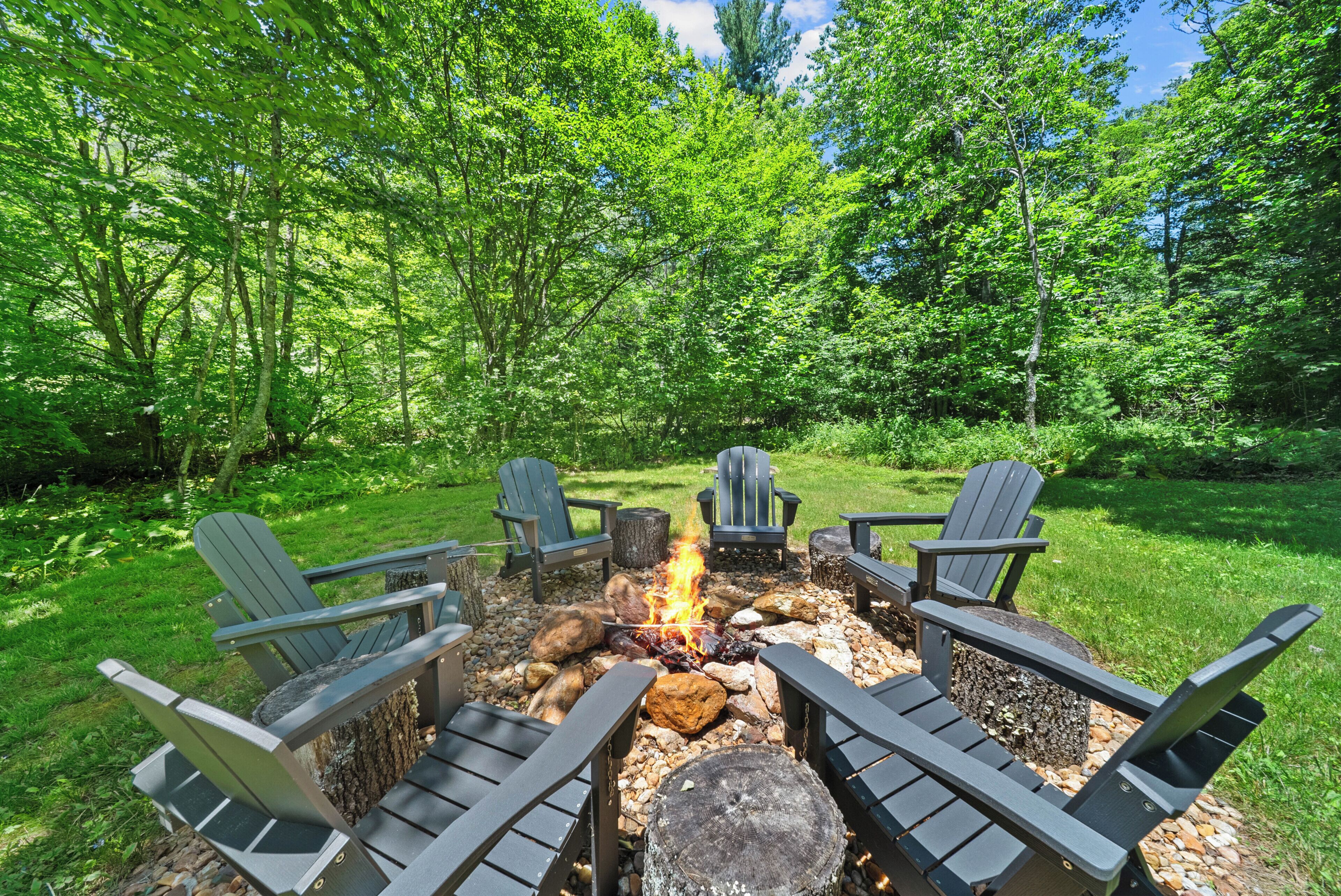 Un foyer entouré de fauteuils Adirondack, situé dans une zone boisée.