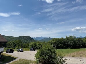 A parking area with vehicles, a building with a sloped roof, and a mountainous landscape in the background. - Terrific 2-bedroom condo with AC in charming Bartlett (Bartlett)
